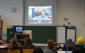 Schüler|innen hören im Klassenzimmer einer Onlineautorenlesung zu